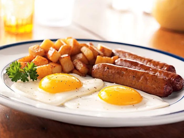 Balanced breakfast: eggs, golden potatoes and grilled sausages cooked with minimal fat